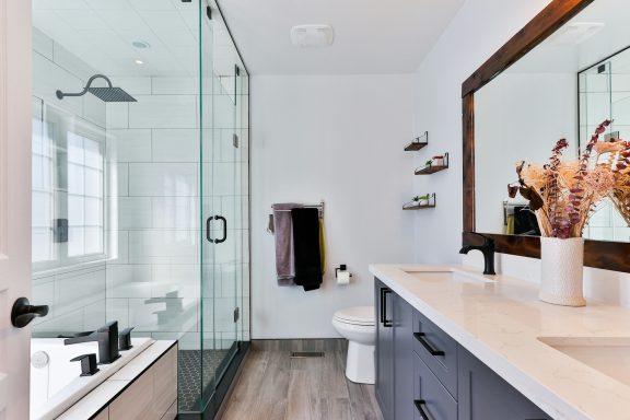 Modern bathroom featuring a glass shower, a large mirror, and decorative flowers.